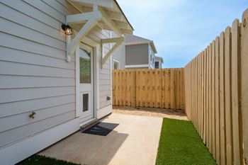 Townhouse with fenced pet yard, backyard, pet door, and turf.